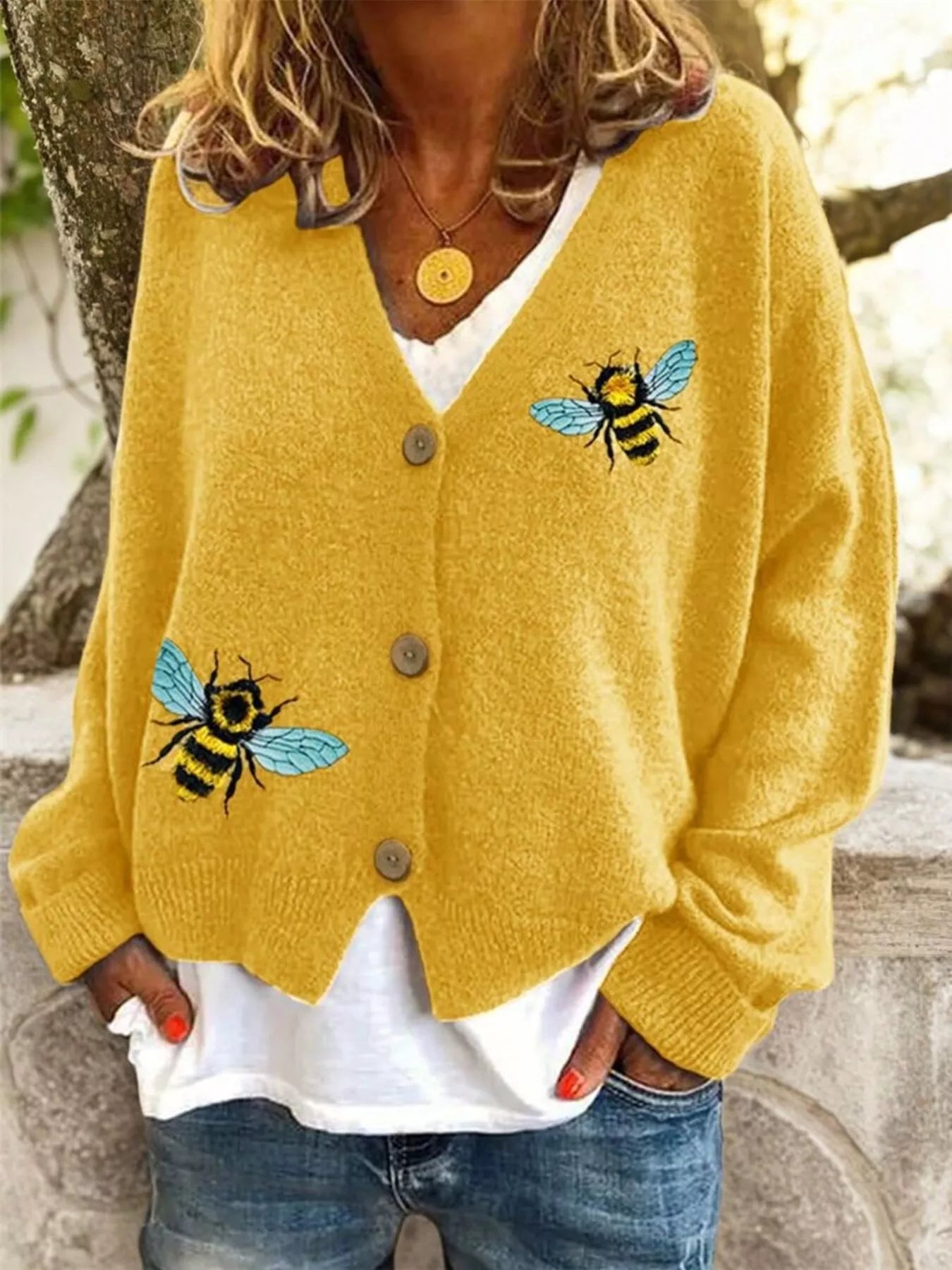 Person wearing a yellow cardigan with bee designs outdoors