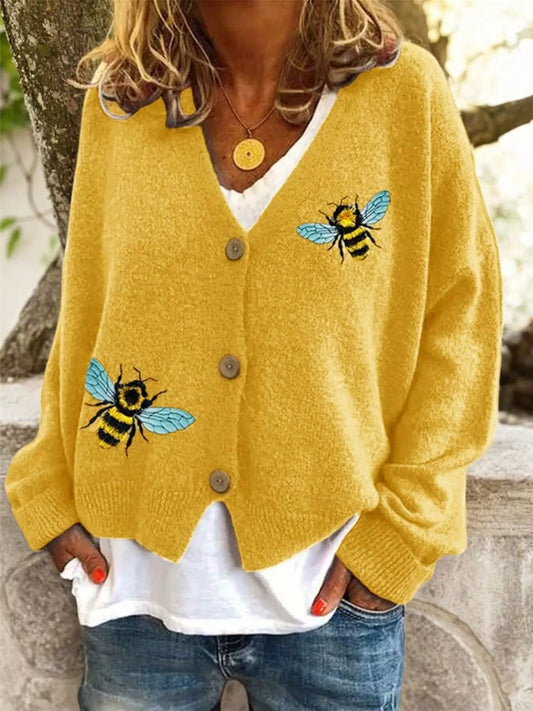 Person wearing a yellow cardigan with bee designs outdoors