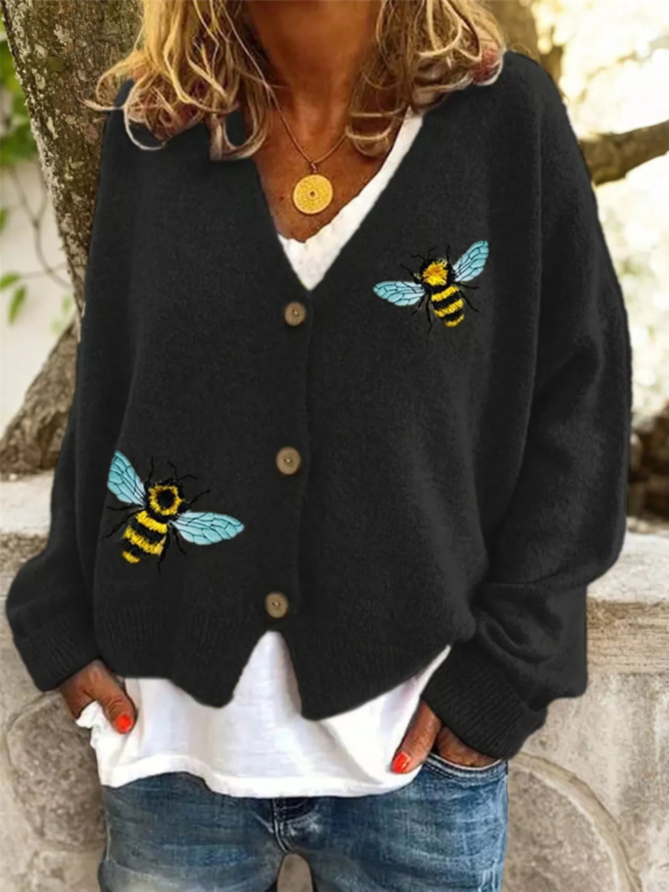 Person wearing a black cardigan with bee designs outdoors