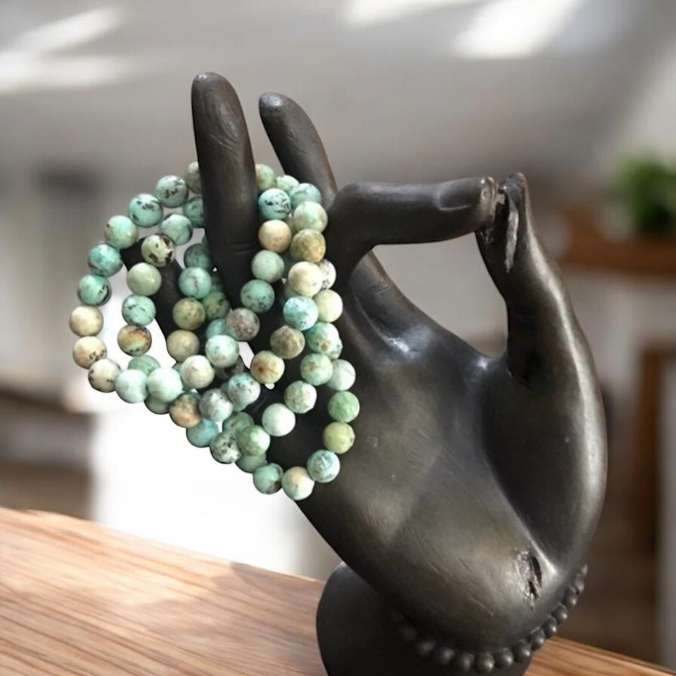 Green beaded bracelets on a bronze hand sculpture