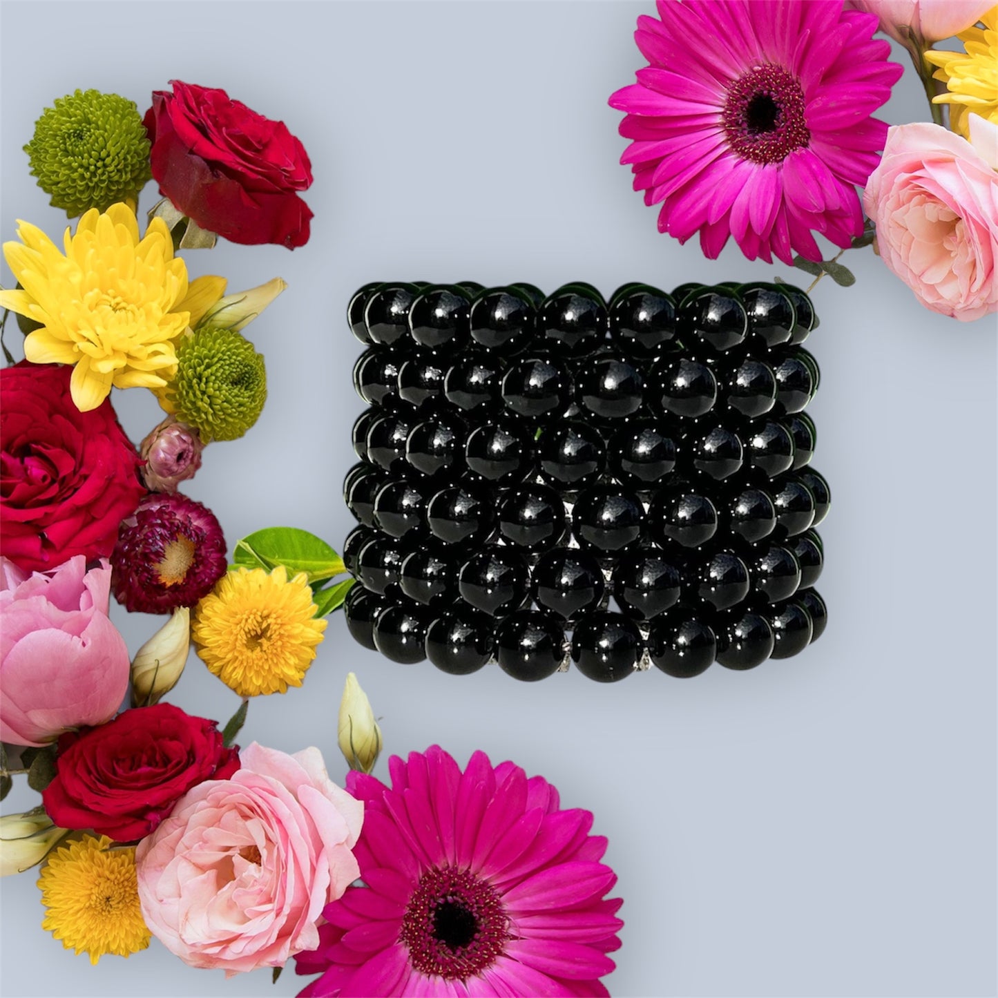 Black onyx bracelets surrounded by colorful flowers on a light gray background